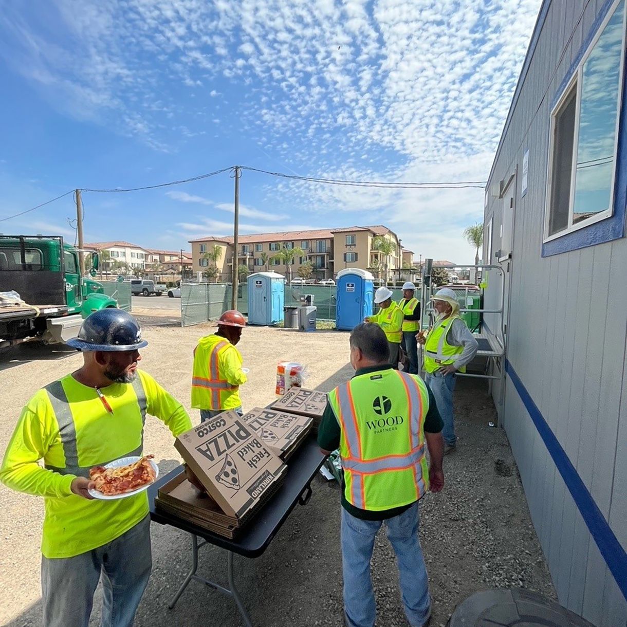 Construction workers eating pizza from pizza boxes at construction site