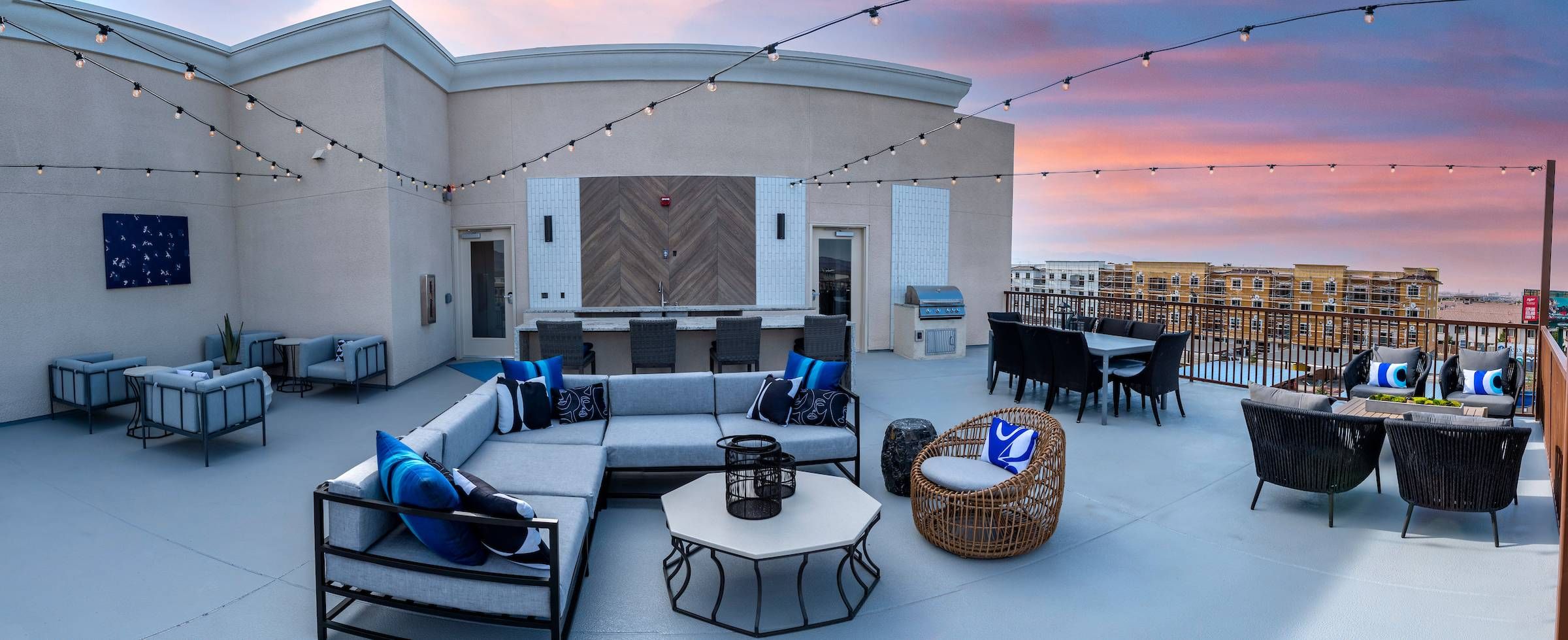 The rooftop terrace at Alta Southern Highlands features comfortable outdoor seating, string lights, and a sunset view.
