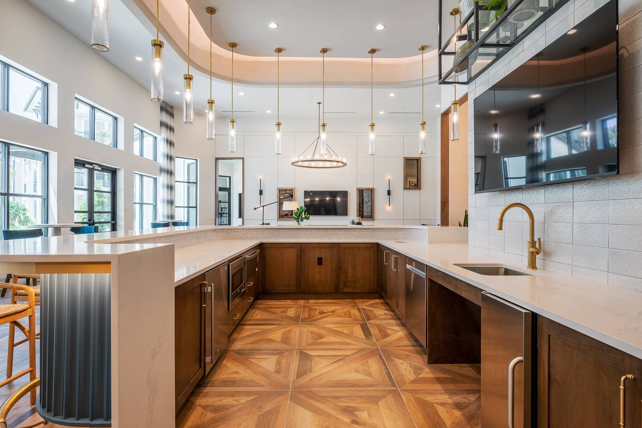 An open-concept kitchen with stainless steel appliances, wood cabinetry, and a curved kitchen island in resident common area at Alta at Horizon West.