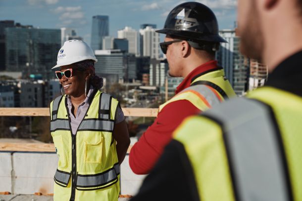 Group of construction workers look up a giant red crane structure