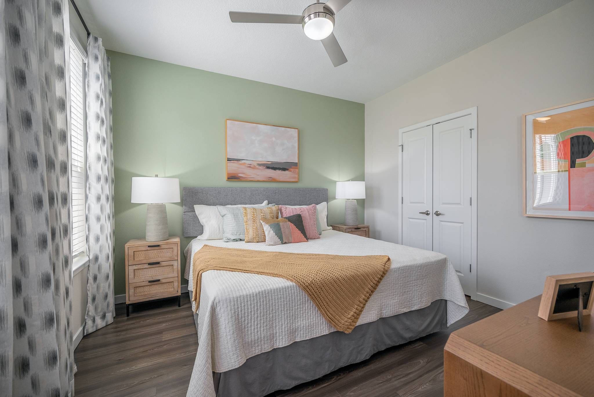 A serene bedroom with a green accent wall, queen-sized bed, and complementary wooden furniture at Alta at Horizon West.
